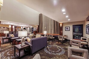 Een hotel lobby met een receptiebalie, een zithoek en een groot raam.