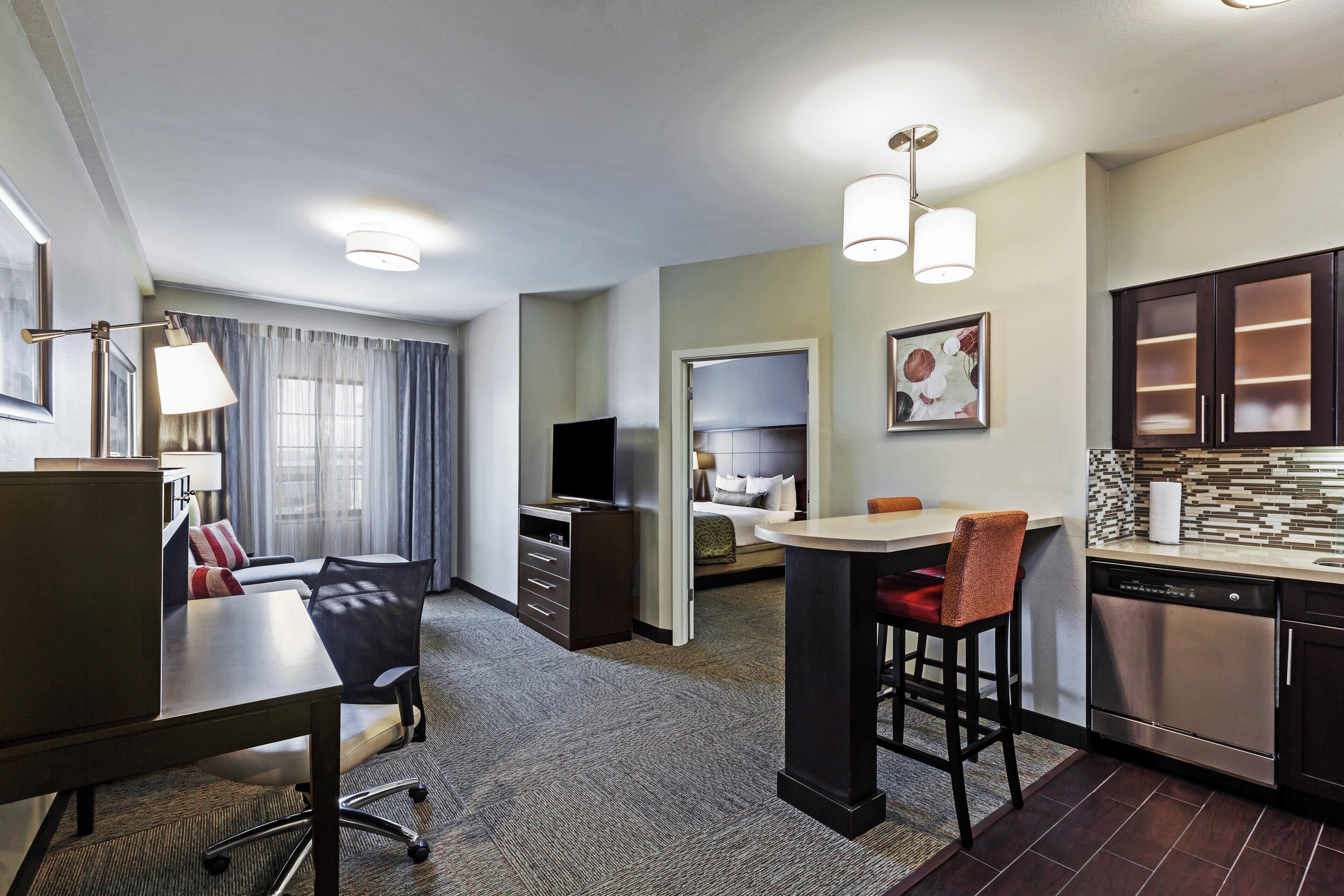Une chambre d’hôtel avec un coin repas, une kitchenette et un lit équipé d’un téléviseur.