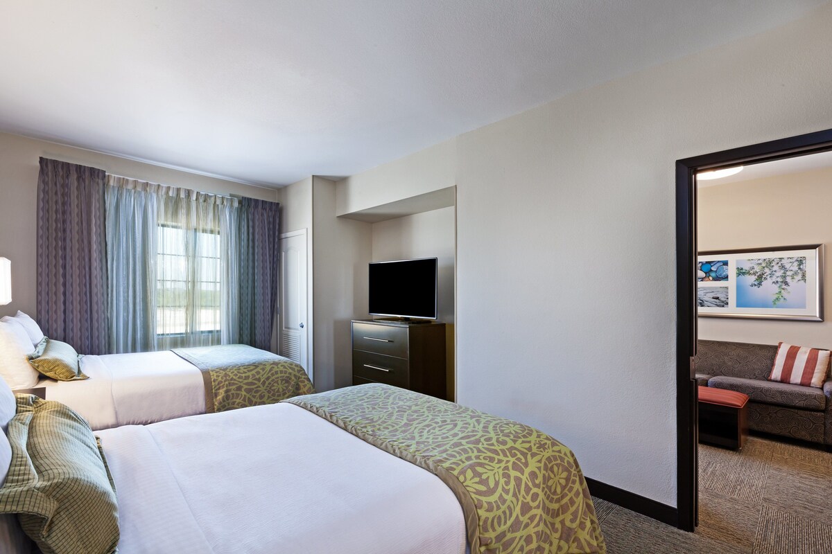 Een hotelkamer met twee bedden, een televisie, een bureau en een bank.