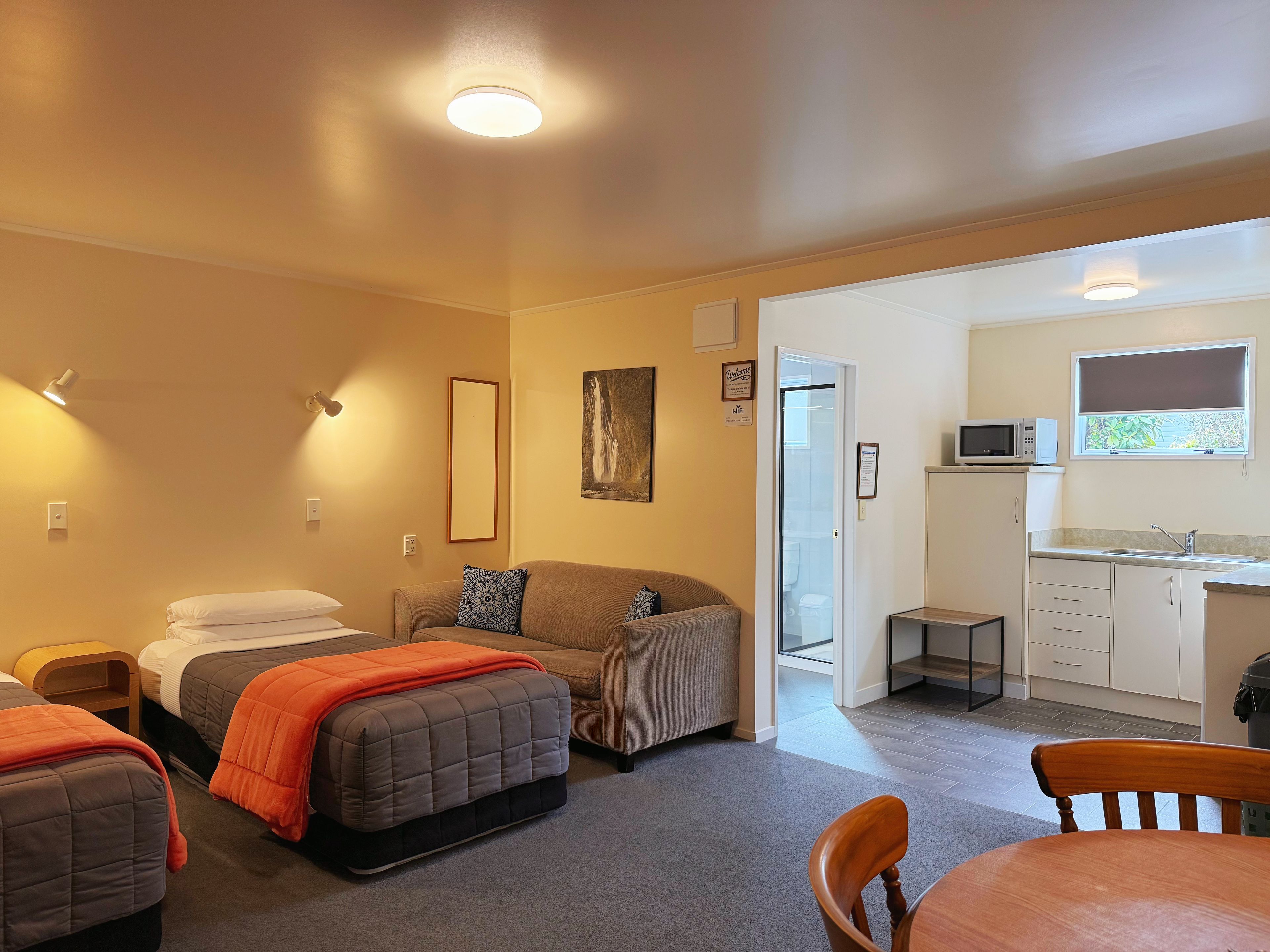 A compact living space with a kitchenette, a sofa, a bed, and a dining area.