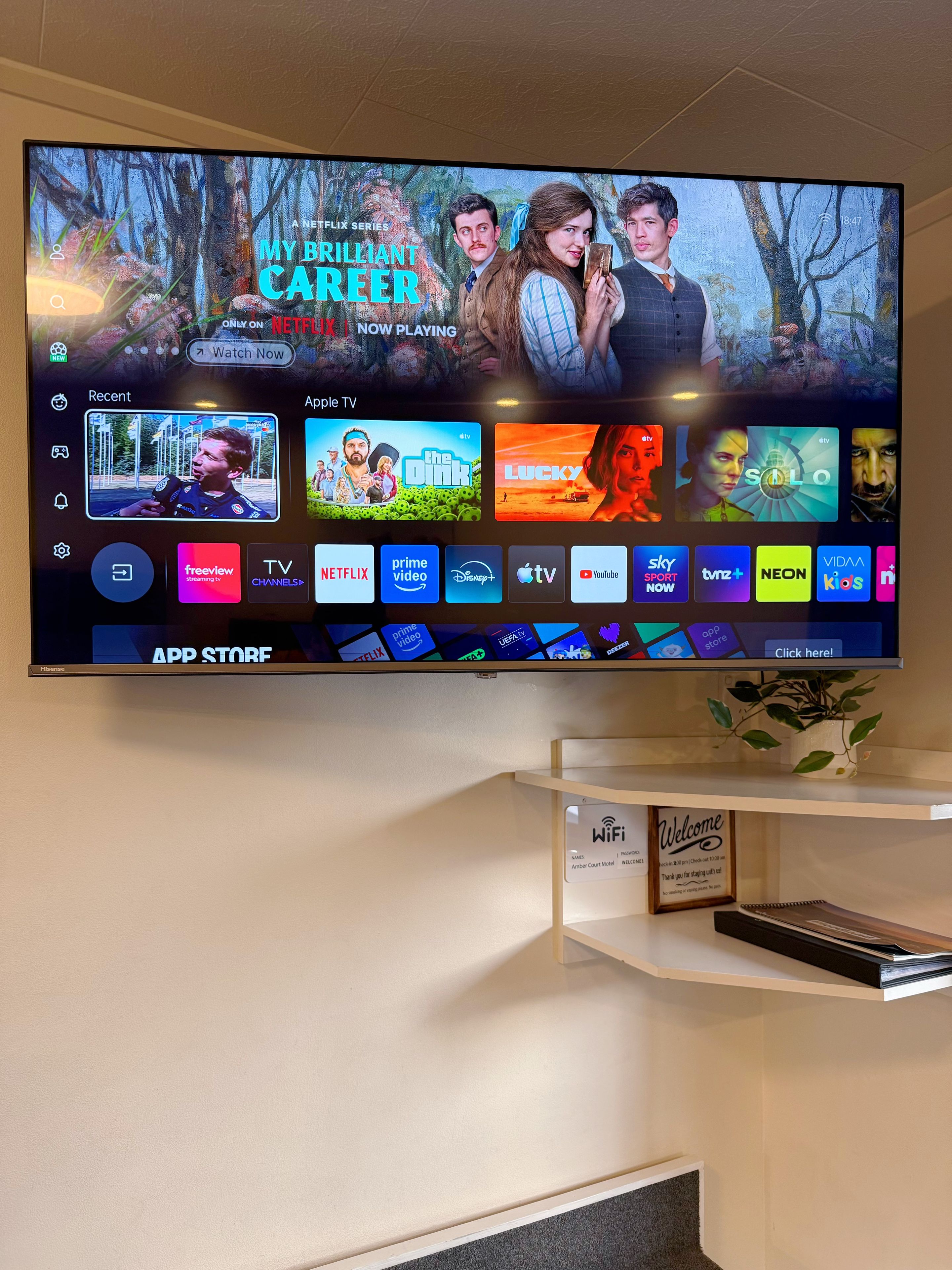 A television mounted on a wall displaying a streaming service interface with various content options.