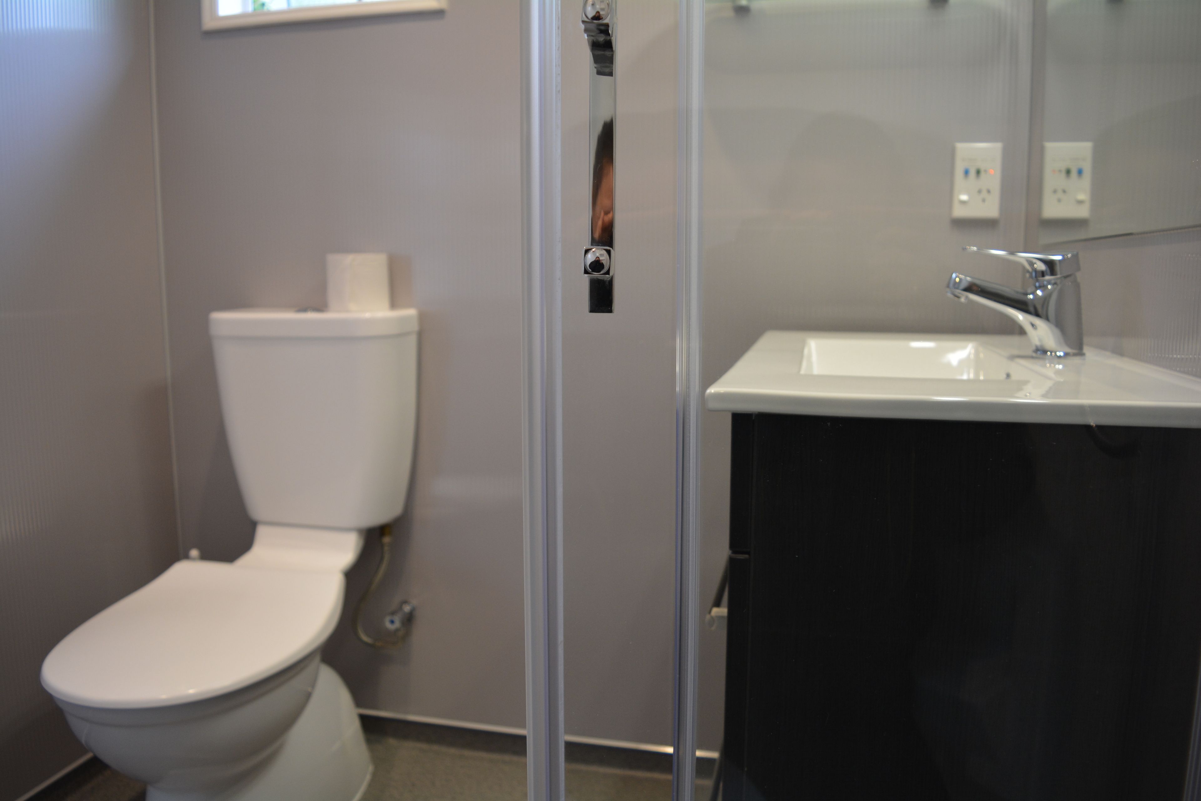 A bathroom with a toilet, a sink, and a mirror.