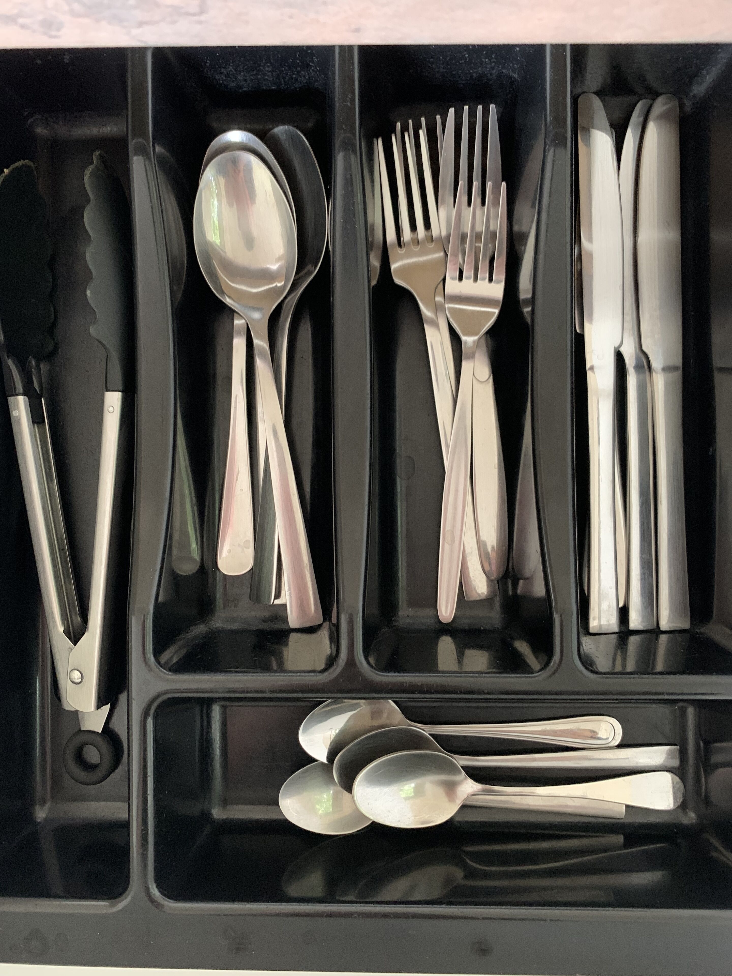 A compartmentalized utensil holder with various kitchen tools.