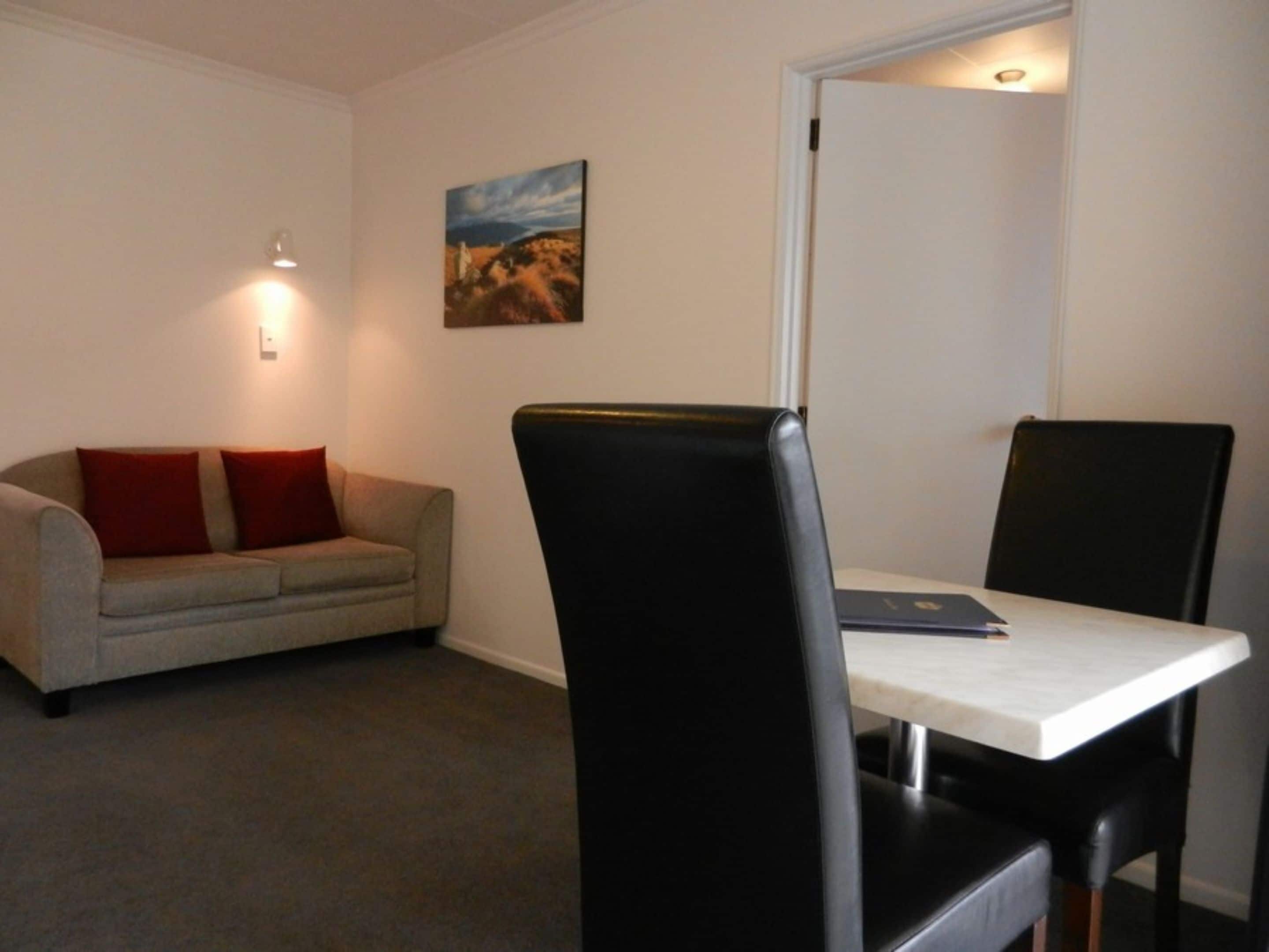 Una habitación pequeña y sencilla con un sofá, una mesa y dos sillas.