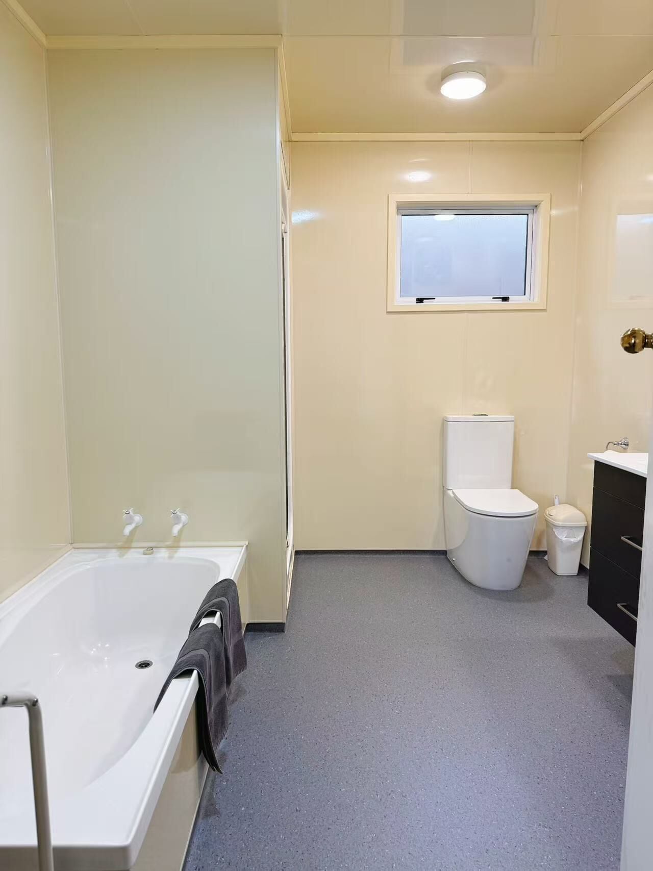 A compact bathroom with a bathtub, toilet, and a small window.