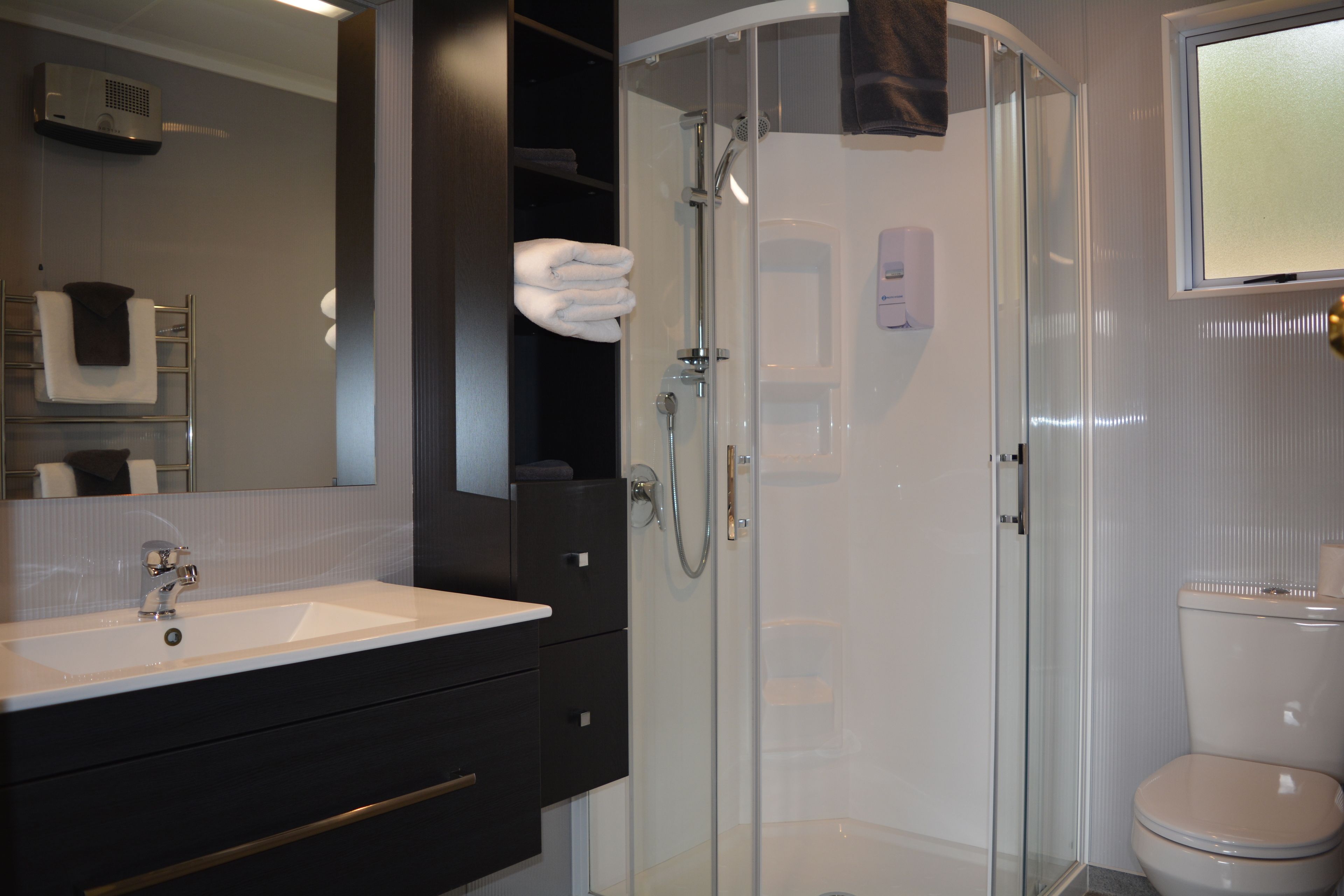 A modern bathroom with a glass-enclosed shower, a white sink, and a toilet.