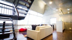 A modern interior with a staircase, a white sofa, and a kitchen area. - Full Circle (Kutchan)