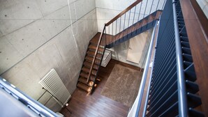 A staircase with wooden steps and metal railings, leading to a landing with a carpeted area. - Full Circle (Kutchan)