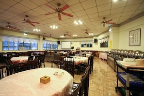 A banquet hall with round tables, ceiling fans, and a buffet area. - Jenq Yang Hotspring Hotel (Ren'ai)