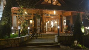 A building with a covered entrance, stone steps, and outdoor seating area with tables and chairs. - The Hill Station Boutique Hotel (Sa Pa)