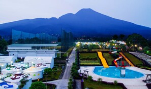 A resort with a swimming pool, a children's play area, and a view of a mountain. - The Highland Park Resort Hotel Bogor (Cilobak)
