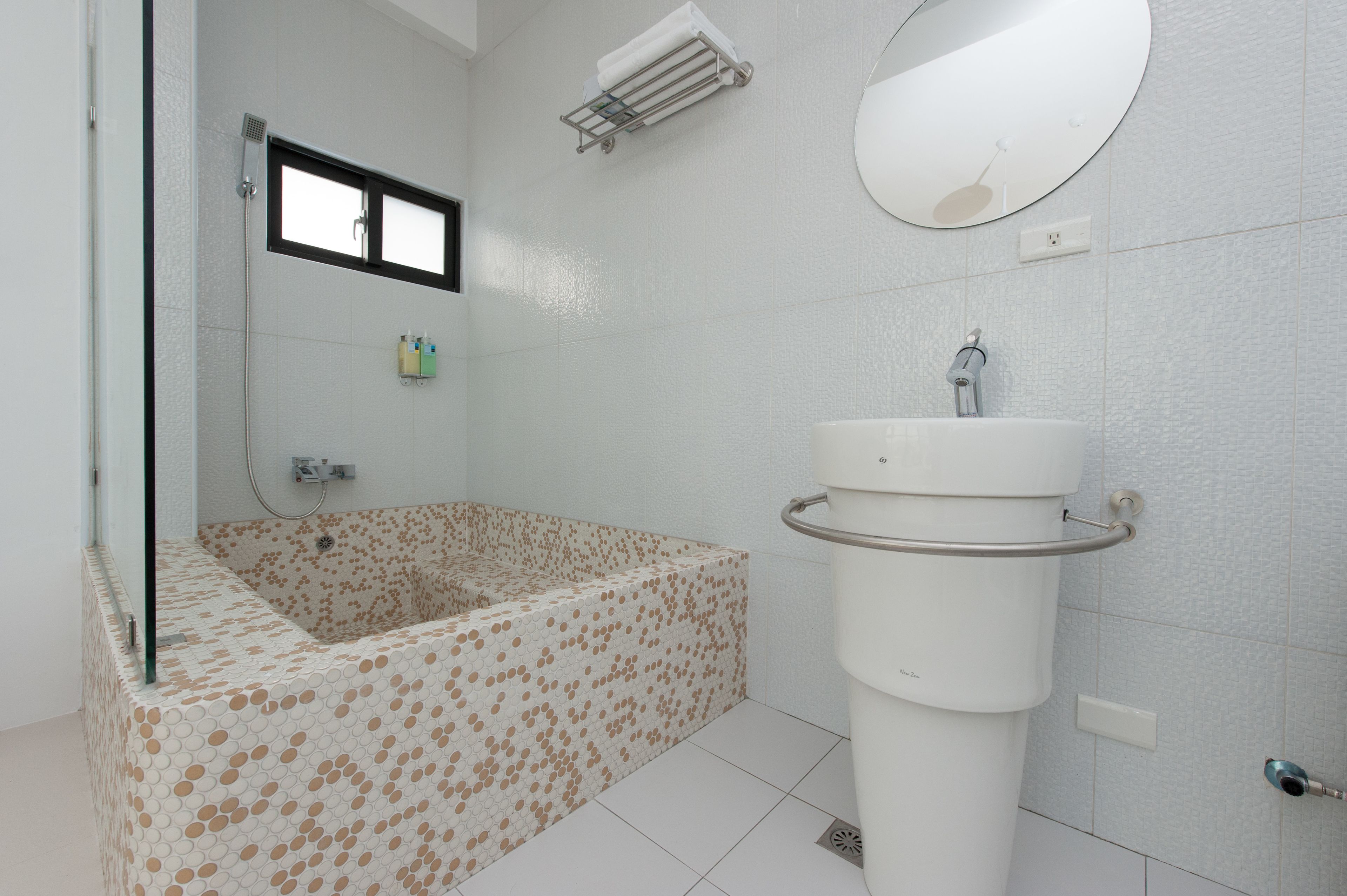 Un baño moderno con una bañera independiente, un lavabo sobre pedestal y un espejo grande.