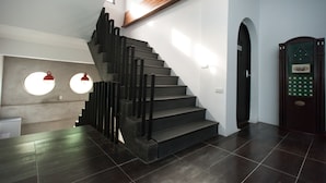 Una escalera moderna con escalones oscuros y barandillas negras, que lleva a una plataforma con un estante de madera.