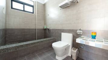 A modern bathroom with a shower, toilet, and a small shelf with toiletries.