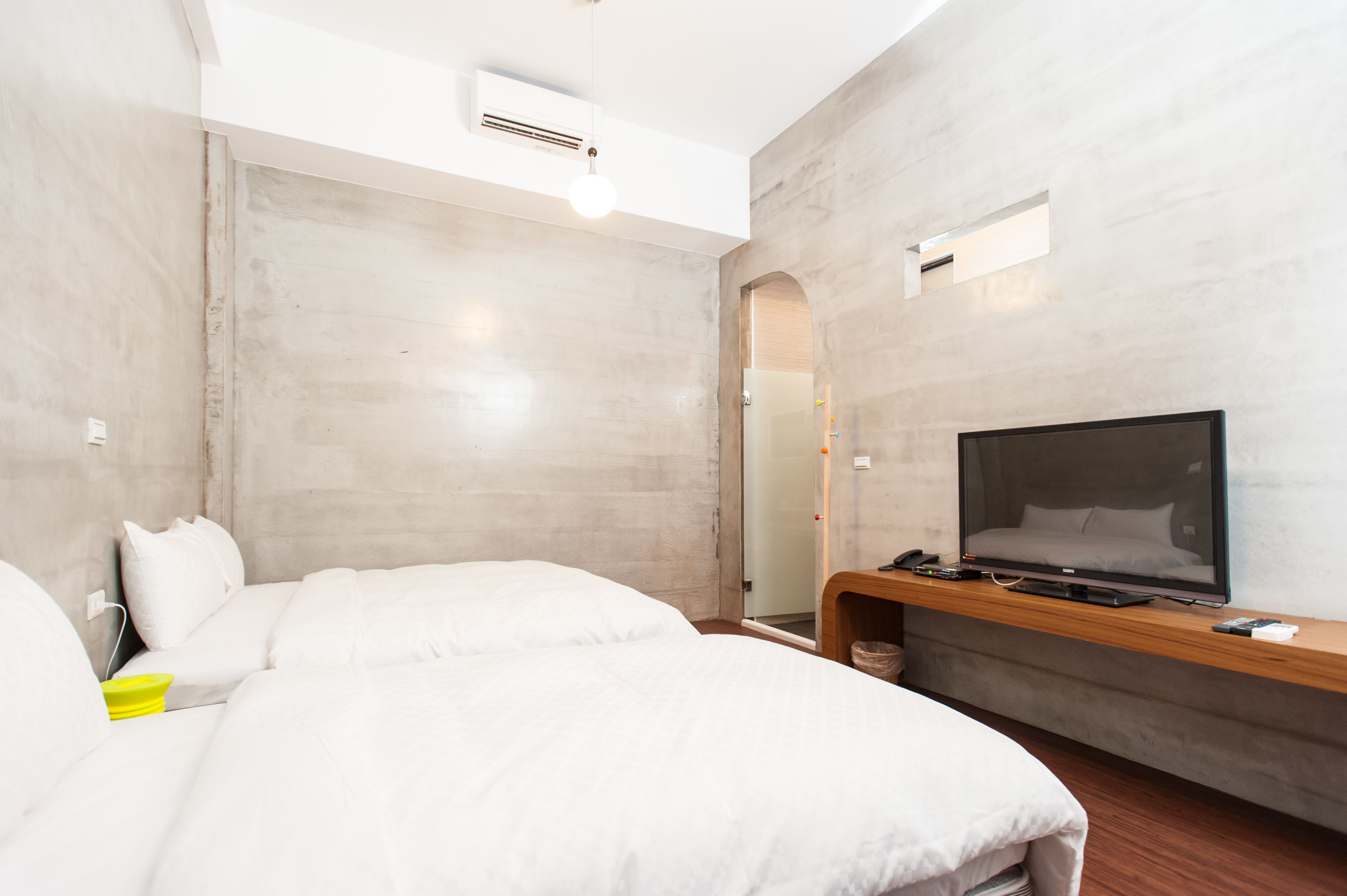 A modern hotel room with a large bed, a flat-screen TV, a wooden console, and a large mirror.