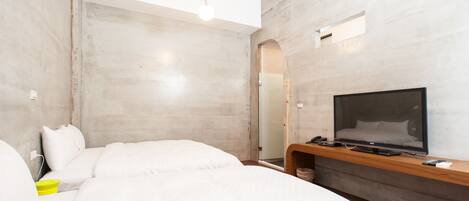 A modern hotel room with a large bed, a flat-screen TV, a wooden console, and a large mirror.
