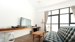 Una sala de estar moderna con un sofá, una mesa de madera, un televisor y una lámpara colgante.