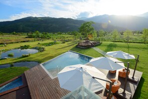 A pool area with a wooden deck, umbrellas, and lounge chairs. - The Silence Manor (Ruisui)