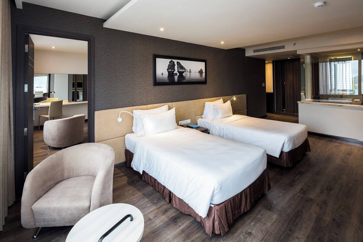 Habitación de hotel con dos camas, un sofá, una silla y un escritorio.