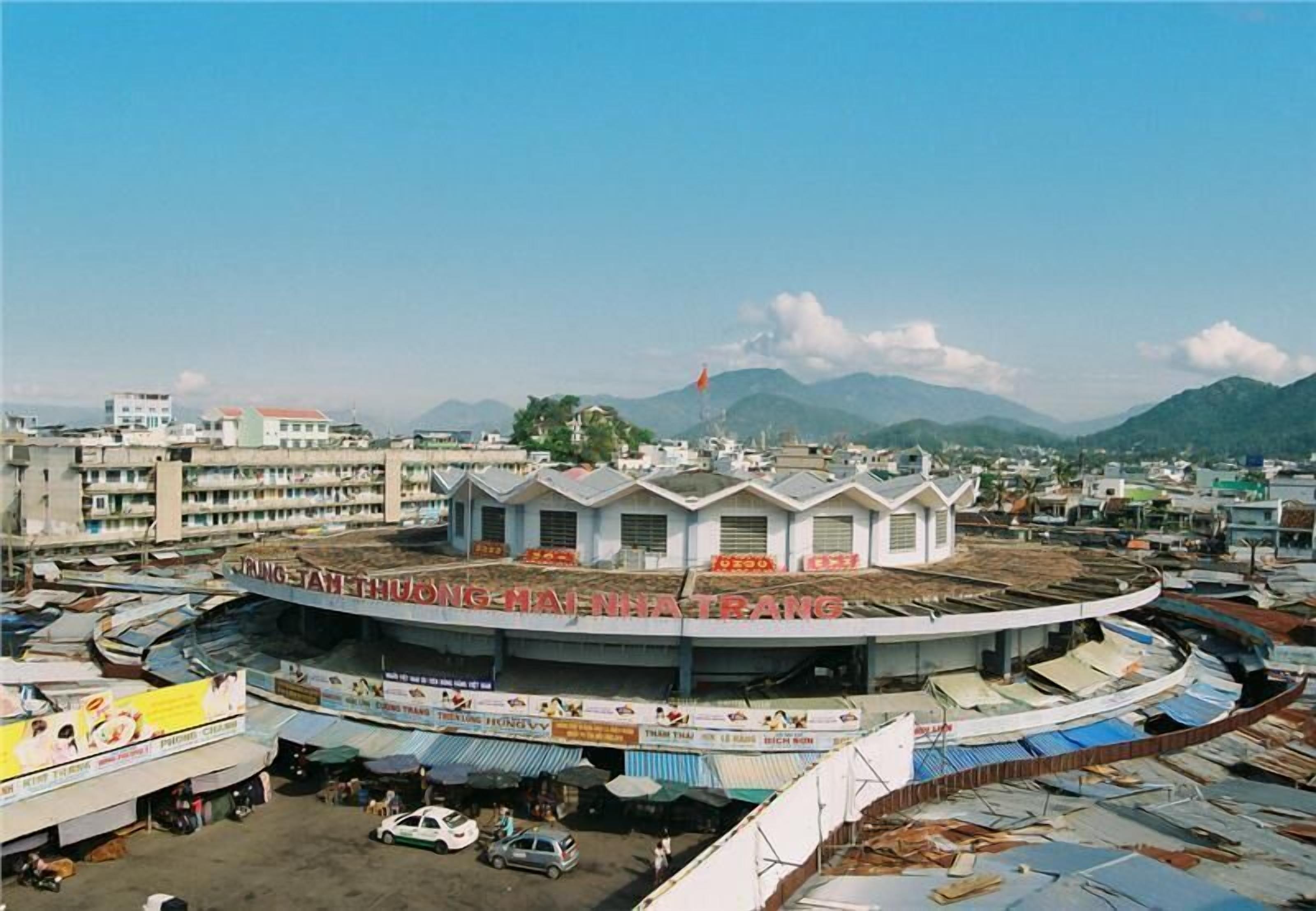 A circular building with multiple levels, surrounded by various shops and vehicles.