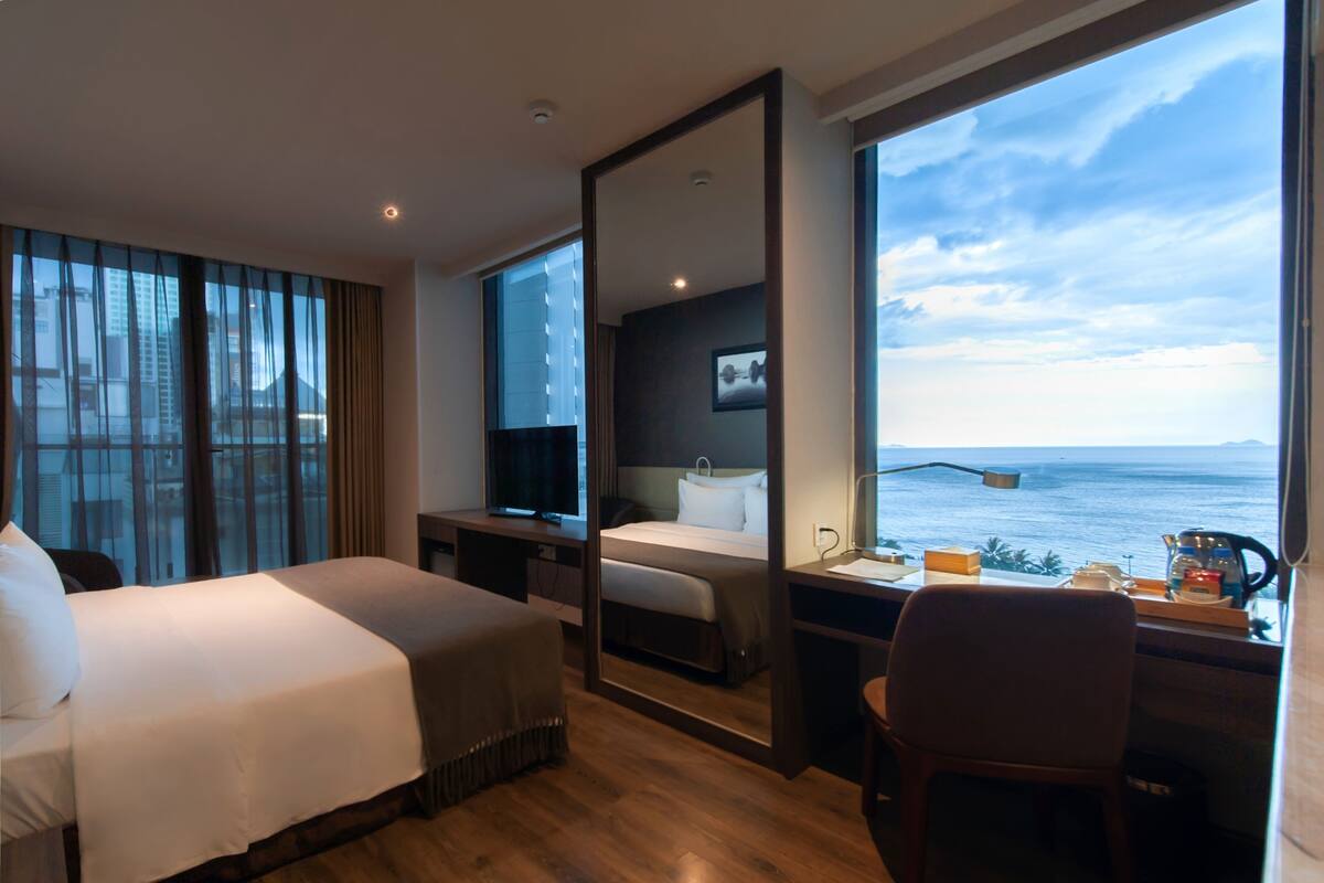 Una habitación de hotel moderna con una cama grande, un escritorio y vistas al mar.