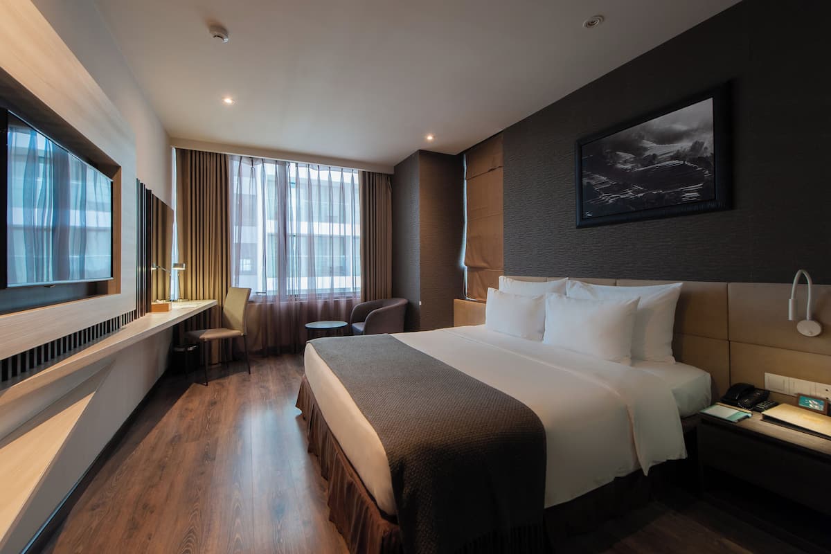 Habitación de hotel con una cama grande, un escritorio, una silla y un televisor.