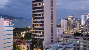 A high-rise hotel with multiple floors, a prominent entrance, and a view of the sea.