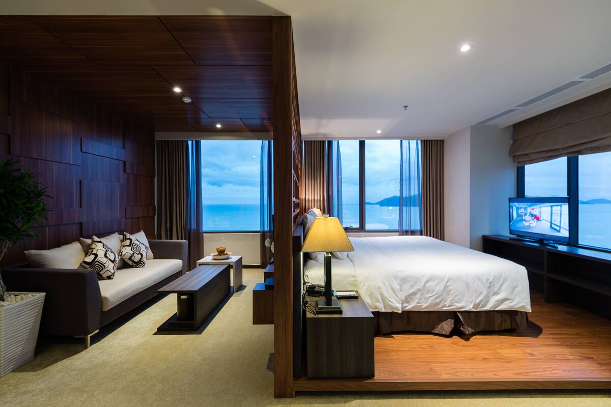 Una habitación de hotel moderna con una cama grande, un sofá, una mesa de centro y un televisor.