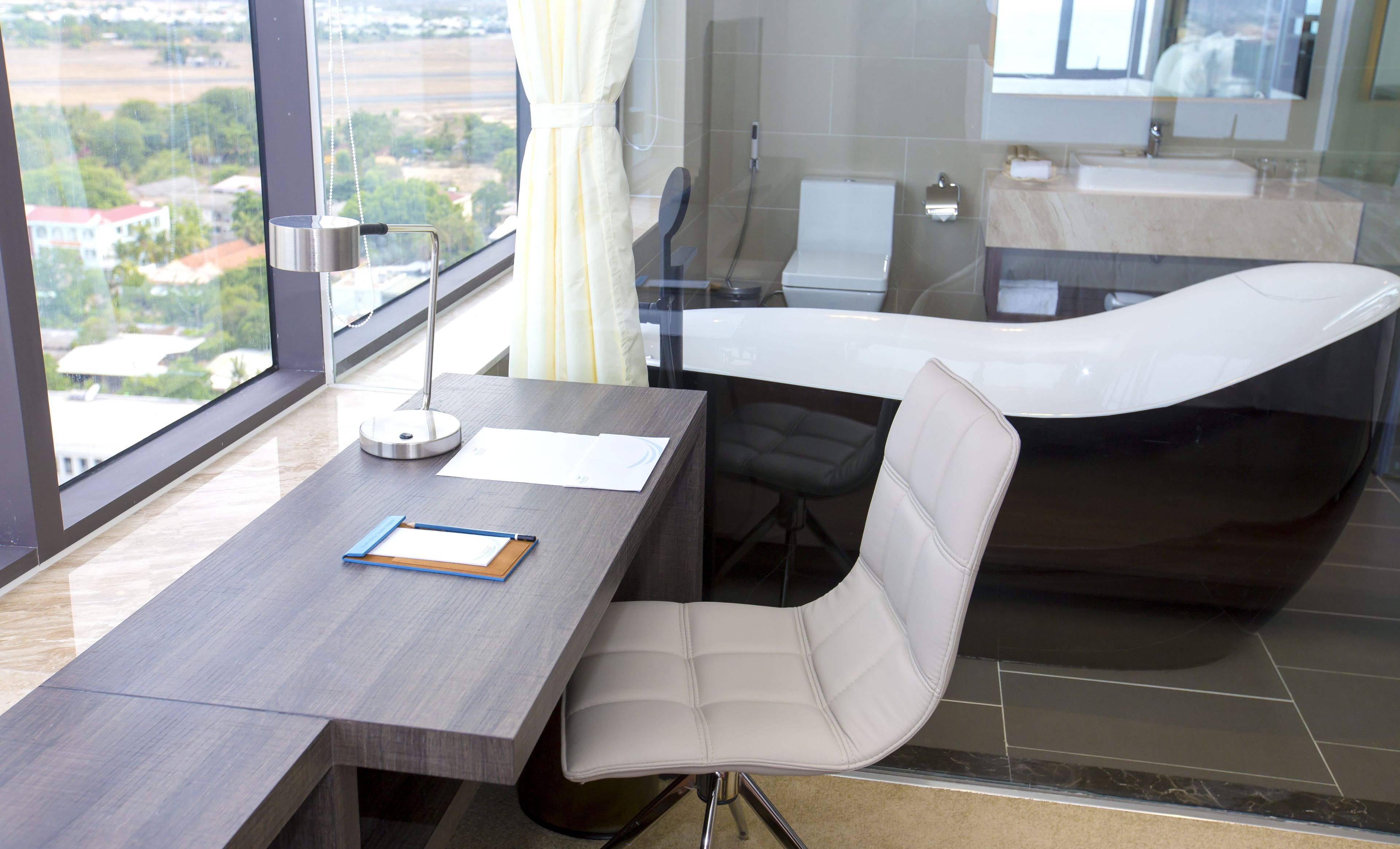 A modern office with a desk, chair, and a large window overlooking a cityscape.