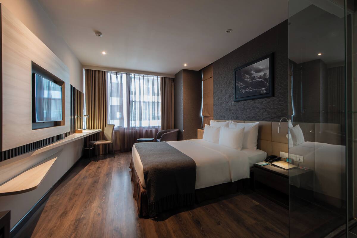 Una habitación de hotel moderna con una cama grande, un escritorio, una silla y un televisor.