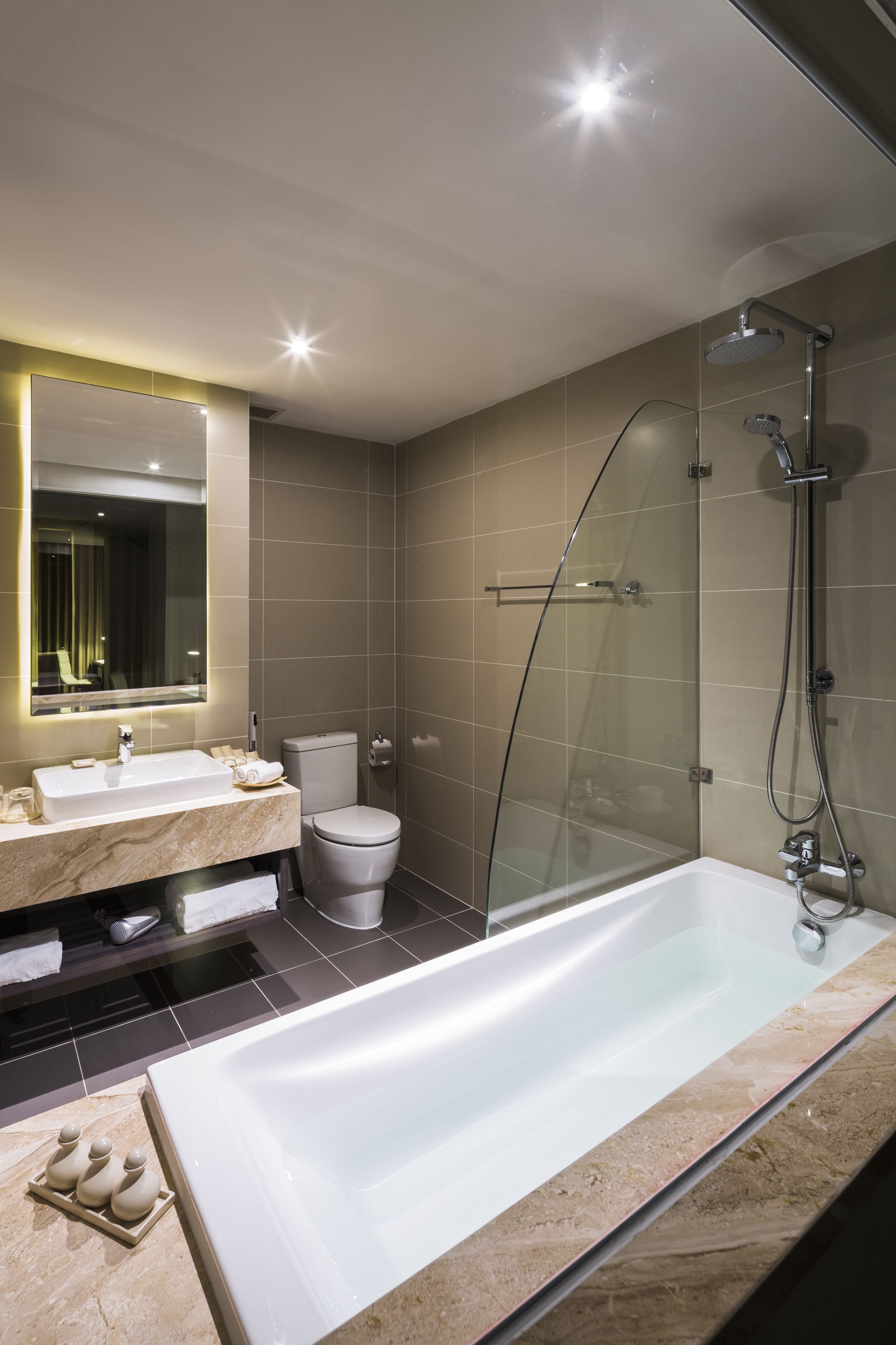A modern bathroom with a glass-enclosed shower, a large bathtub, and a vanity with a mirror.