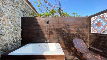 Una terraza de madera con un jacuzzi y una silla de descanso.