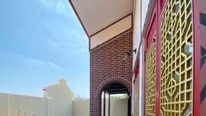 Un balcon fermé, doté d’une rambarde en métal, d’un mur en briques et d’un portail décoratif.