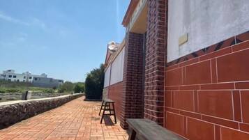 Un edificio de ladrillo con un banco y un taburete en una zona pavimentada.