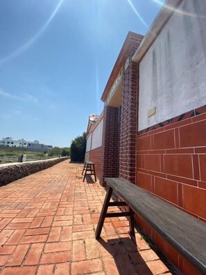 A brick building with a bench and a stool on a paved area. - Murraya Paniculata Villa (Magong)