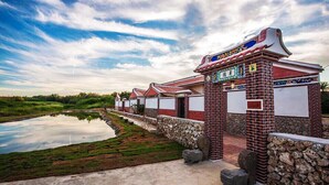 A traditional building with a tiled roof, a stone pathway, and a pond.