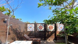 Une terrasse en bois avec un jacuzzi, un banc et une clôture à motifs.