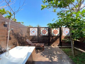 Una terraza de madera con un jacuzzi, un banco y una valla decorativa.