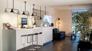 Una cocina moderna con una isla central, taburetes de bar, iluminación colgante y un amplio ventanal con vistas.