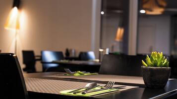 A dining table with a green placemat, cutlery, and a small potted plant.