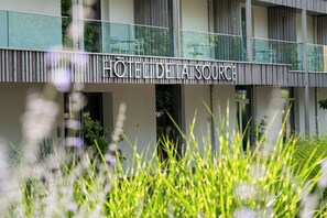 Een hotel met een moderne gevel, een duidelijke ingang en een balkon met zitplaatsen.