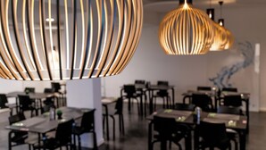 Un comedor moderno con varias mesas y sillas, que destaca por una lámpara colgante con un diseño único y acanalado.