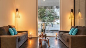 Una sala de estar moderna con dos sofás, una mesita de centro y dos lámparas de pie.