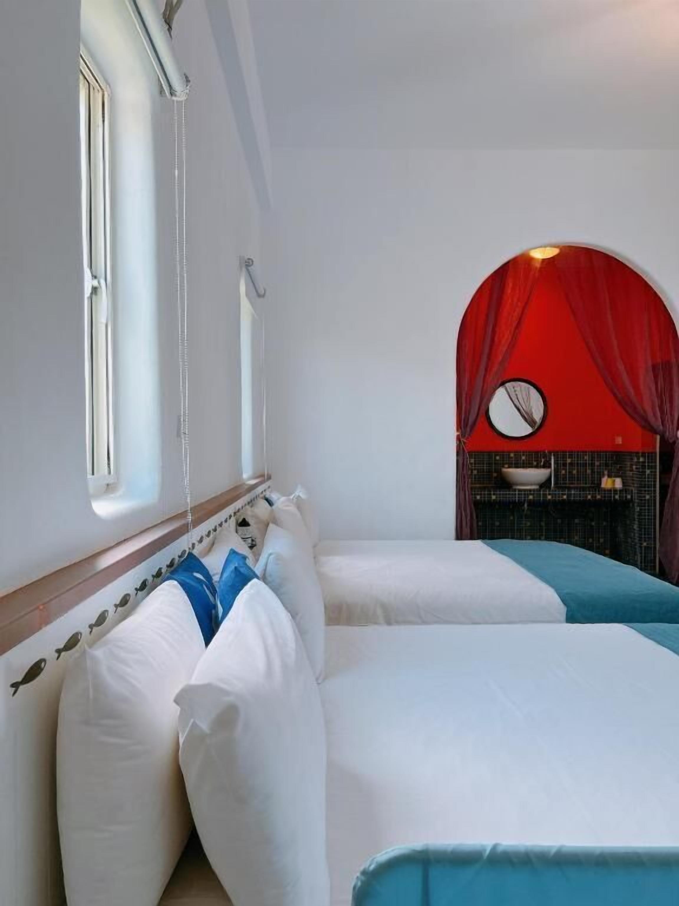 A room with two beds, a window, and a red archway.