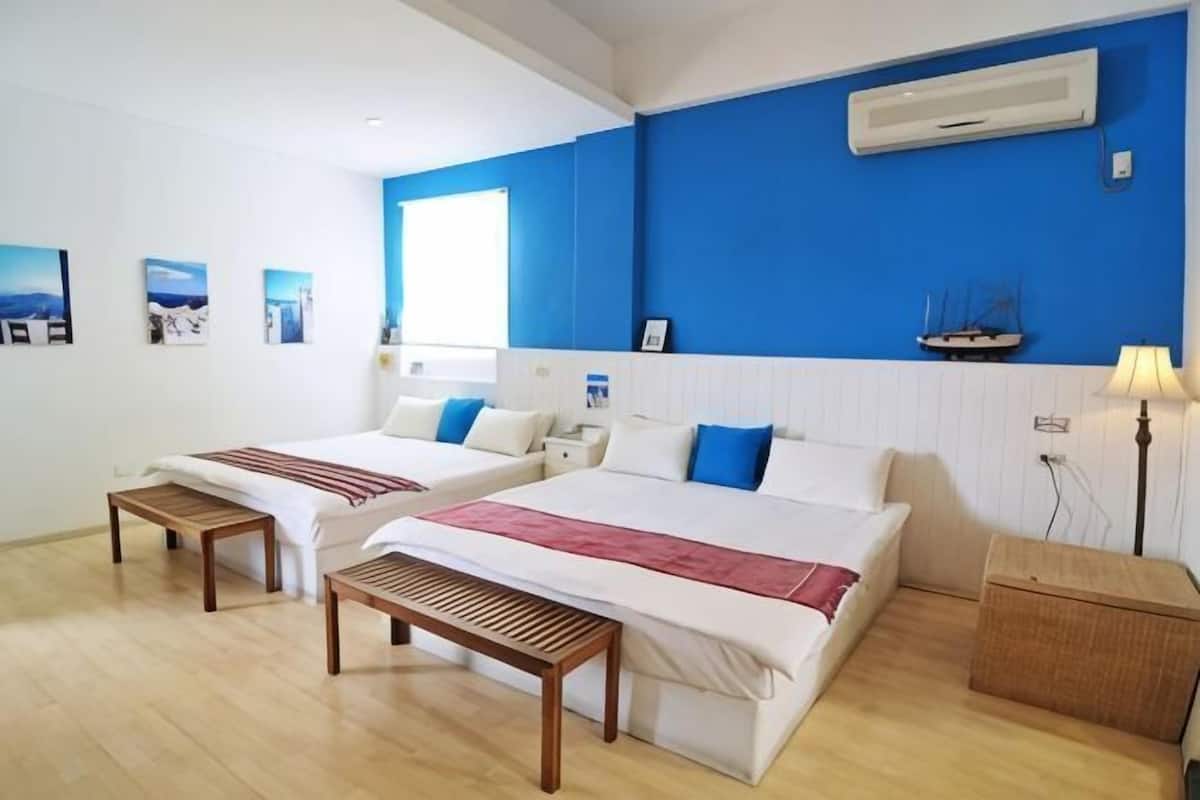 Habitación de hotel con dos camas, una ventana, aire acondicionado de pared y una mesita de noche.