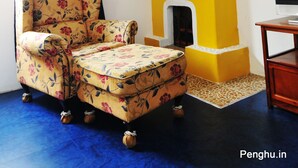 A room with a floral armchair, a yellow fireplace, and a blue curtain. - Greek frontier villa (Magong)