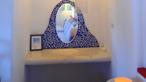 A bathroom with a white vanity, a mirror with a blue mosaic frame, and a towel rack. - Greek frontier villa (Magong)