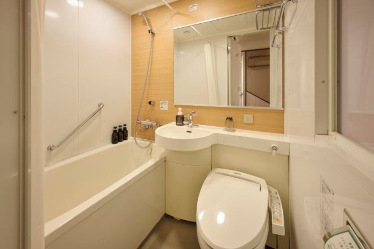 Une petite salle de bain avec une baignoire, des toilettes, un lavabo et un miroir.