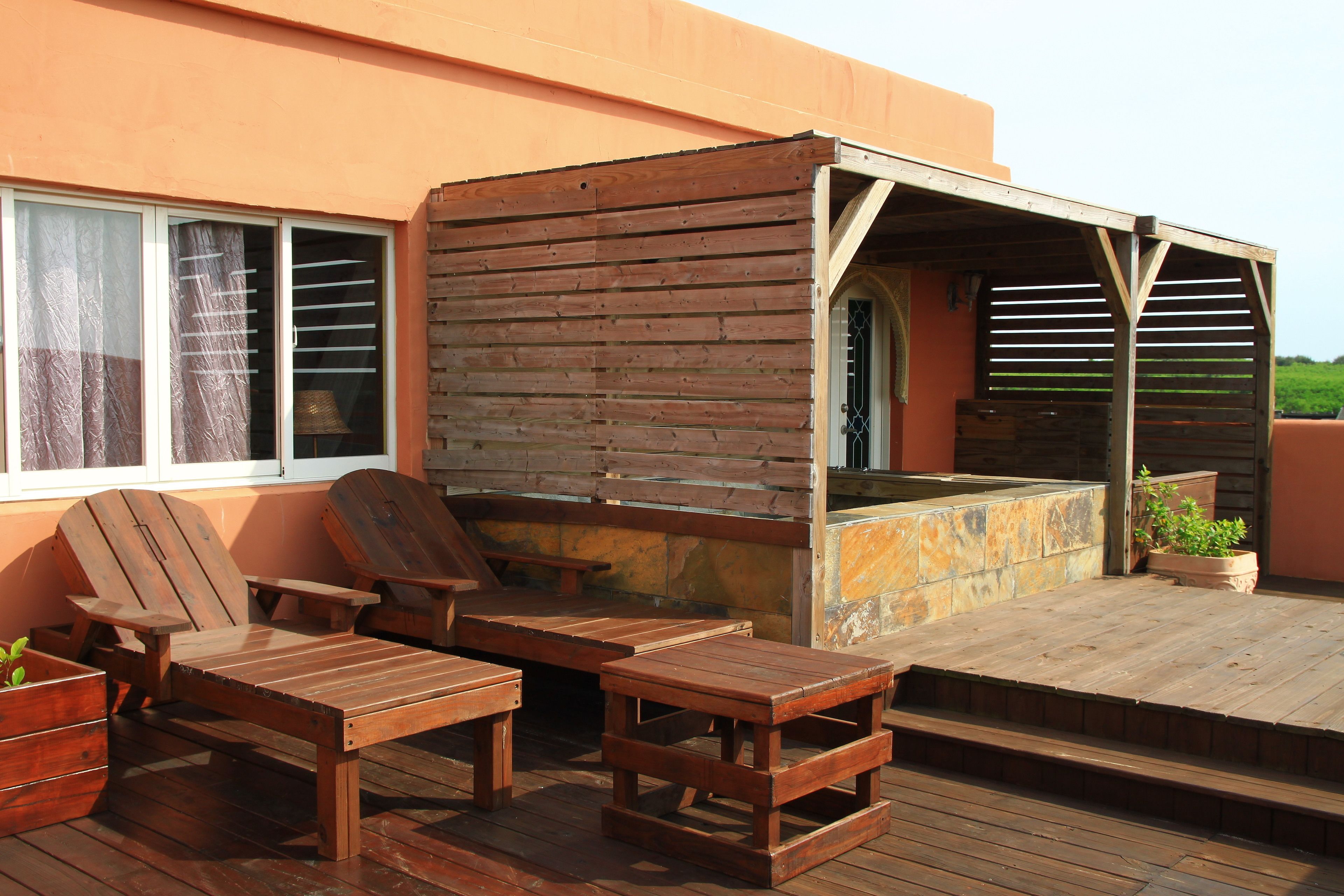 A wooden deck with outdoor furniture, including chairs and tables, and a covered barbecue area.