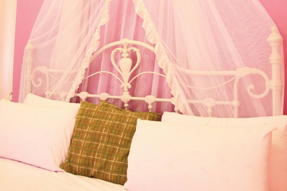 A bed with a white canopy and a green pillow.